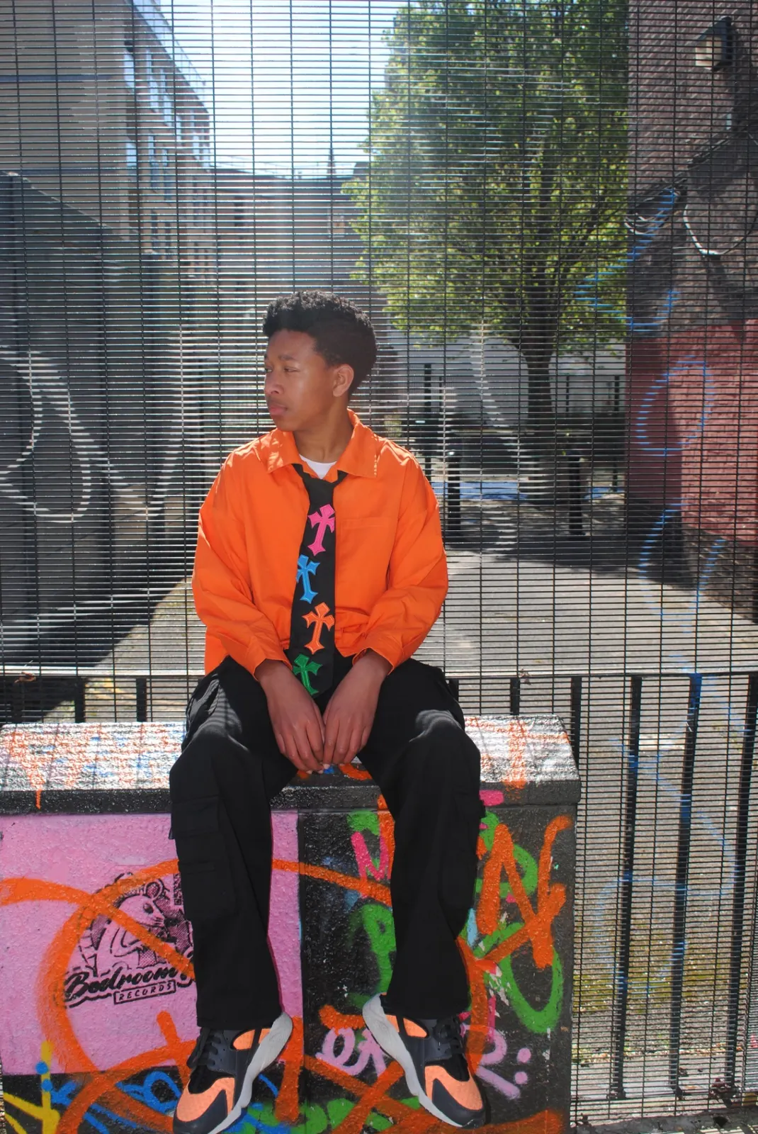 Editorial portrait — reworked cross tie against graffiti backdrop